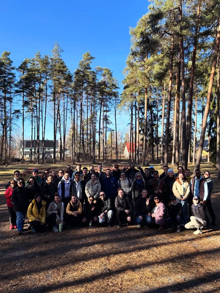About fifty Stay Larsen residents posing together among tall pines in Aegviidu